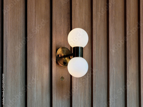 Modern wall sconce with two frosted glass bulbs mounted on a wooden panel wall, showcasing minimalist lighting design in a stylish interior.