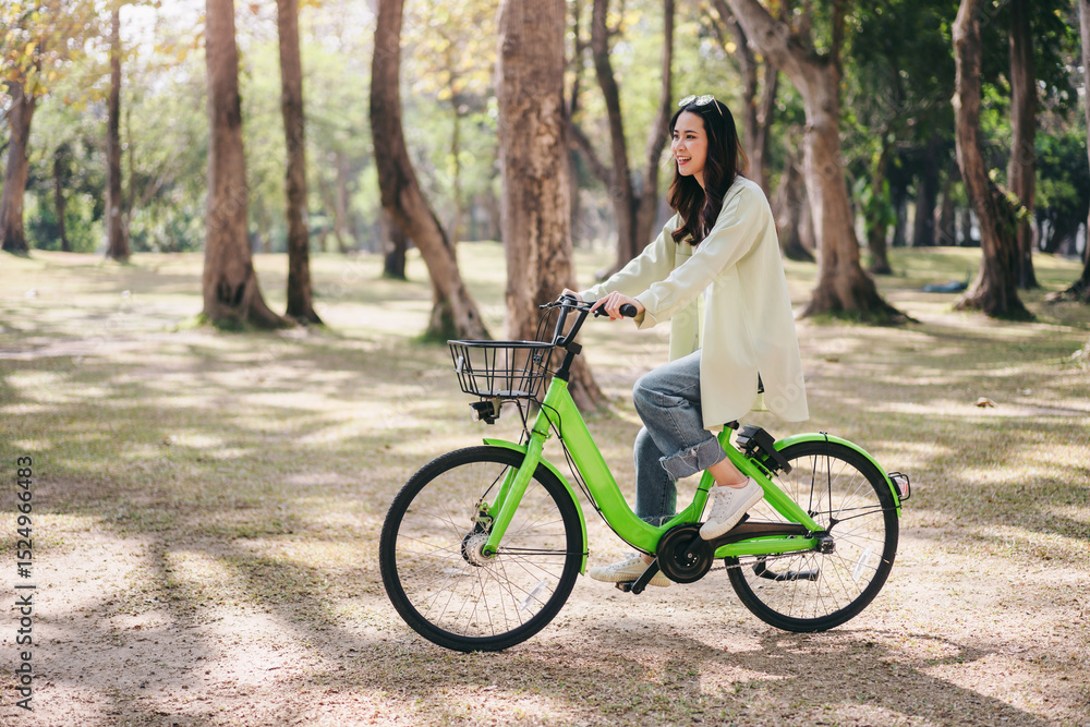 Fototapeta premium A woman is riding a green bicycle in a park