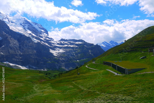 magnificent mountain landscape with snow-capped peaks, white clouds and blue sky in sunny day in summer, Jungfraujoch, Switzerland