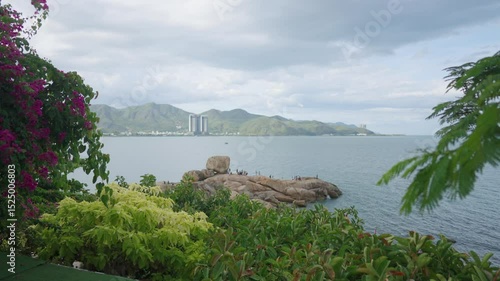 A scenic ocean view with lush greenery, beautiful foliage, and a striking rocky outcrop