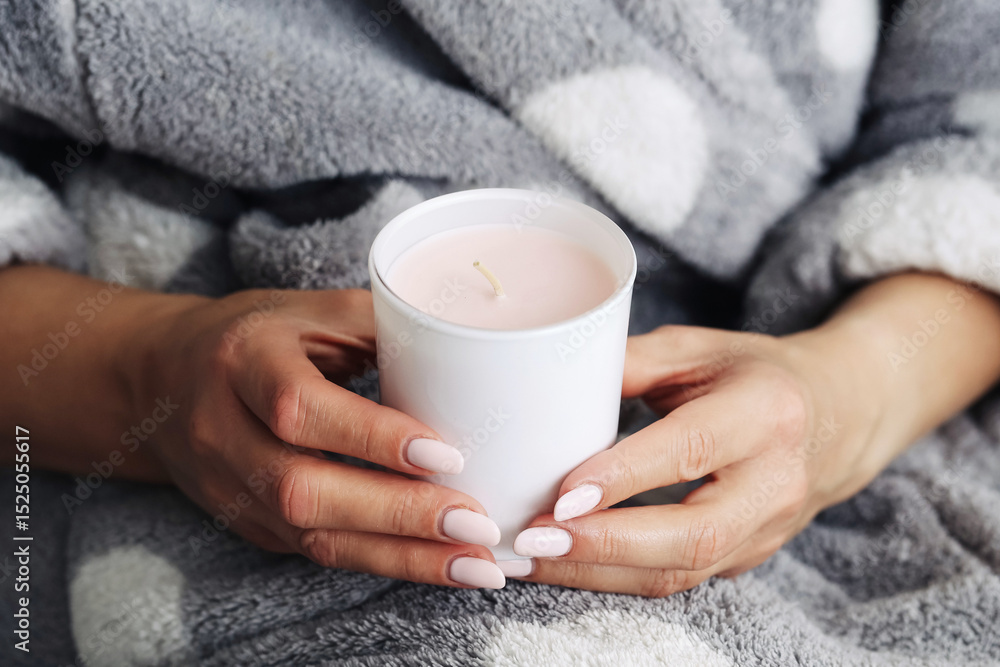 Scented candle in hands. Woman holding candle gently. Soft fleece blanket background. Cozy home moment. Relaxing atmosphere. Warm light. Calm indoor comfort. Scented candle in hands. Woman holding candle gently. Soft fleece blanket background. Cozy home moment. Relaxing atmosphere. Warm light. Calm indoor comfort.