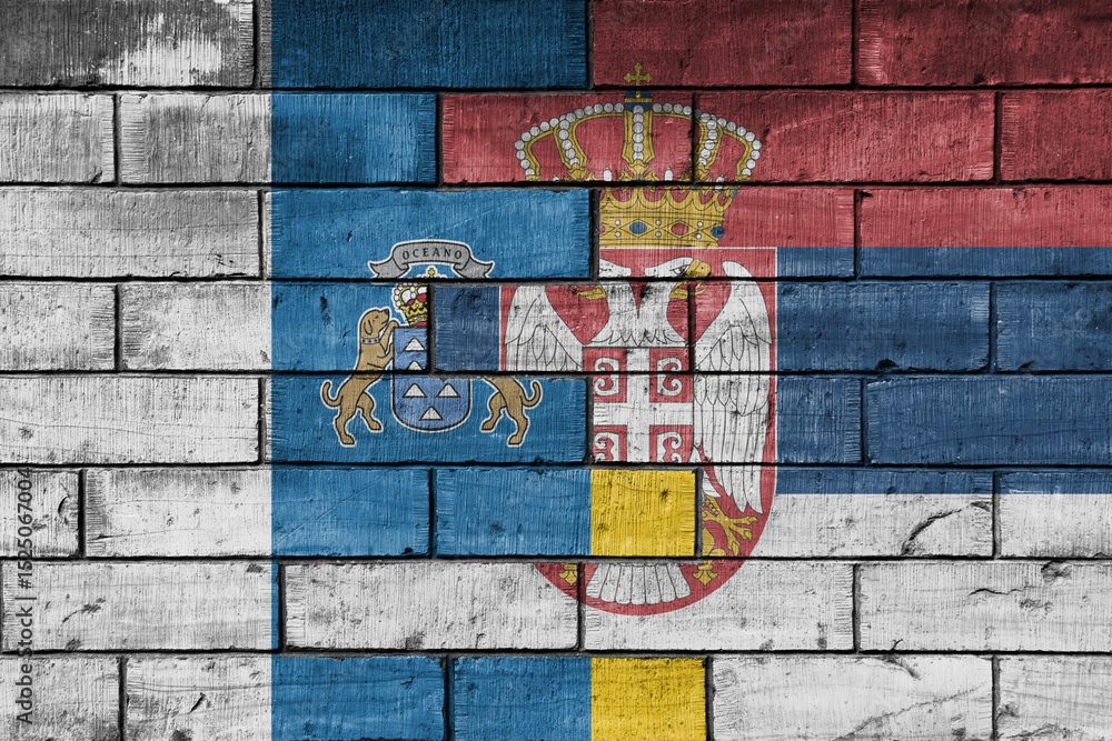 Fototapeta premium colourful painted big national flag of canary islands and flag of serbia on a massive old brick wall background. concept