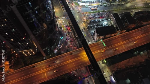 Aerial top view of skycrapper with reflection in glass busy traffic at night in big city, rush hour traffic, 4k