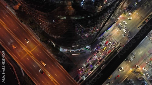 Aerial top view of skycrapper with reflection in glass busy traffic at night in big city, rush hour traffic, 4k