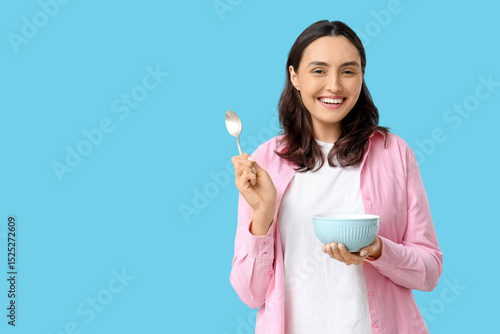 Young woman with tasty soup on blue background