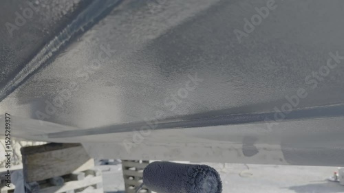 Applying epoxy primer to boat hull with roller at the boatyard