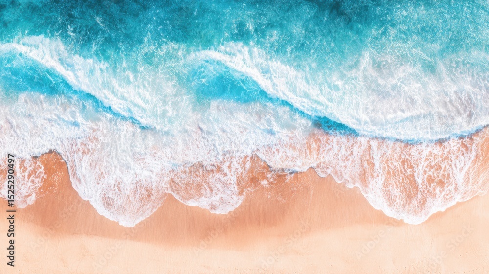 Obraz premium Aerial view of a serene coastline where turquoise and deep blue ocean waters meet a golden-brown sandy shore, with gentle waves creating white foamy crests that contrast beautifully against the clear 