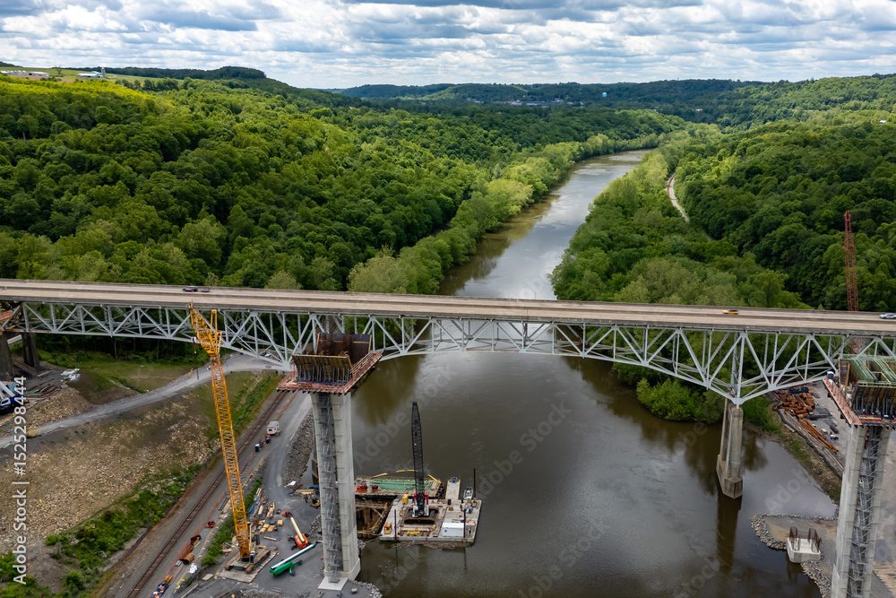 Fototapeta premium Crane lifting materials on bridge over river.
