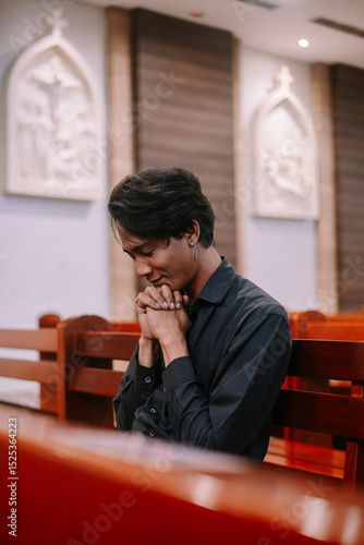 Fotografia Young man praying solemnly inside church seeking solace and comfort