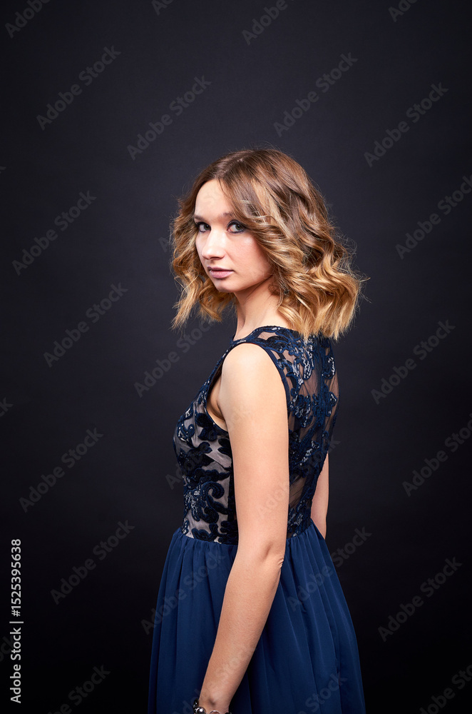 A woman in a black dress poses in a studio against a dark background. She has a beautiful athletic figure. A woman in a black dress poses in a studio against a dark background. She has a beautiful athletic figure.