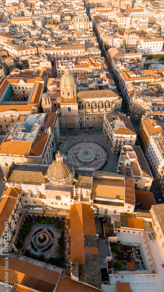 Fototapeta premium Aerial view of Piazza Pretoria in Palermo, Sicily, with its iconic fountain, baroque buildings, and the dome of San Giuseppe dei Teatini glowing in warm morning light