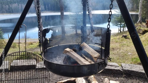 campfire with birch tree log smoke and lake background