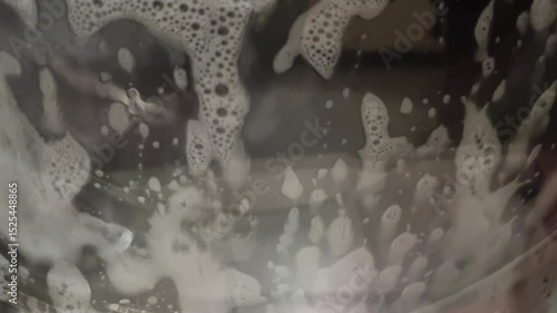 Soap and foam inside washing machine with clothes