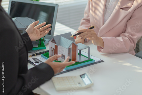 Bilde på lerret Inside a real estate office a real estate agent is using a house mockup to present the design and promotions that the client will receive when they sign sales contract