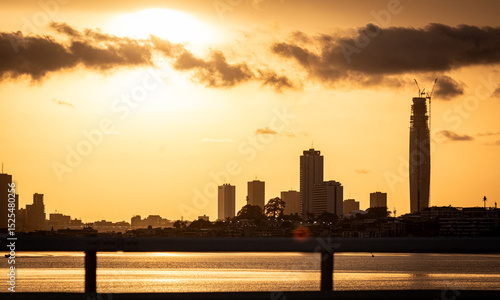 Abidjan at sunset featuring the iconic F Tower under construction, seen from across the Ébrié Lagoon. 2025.