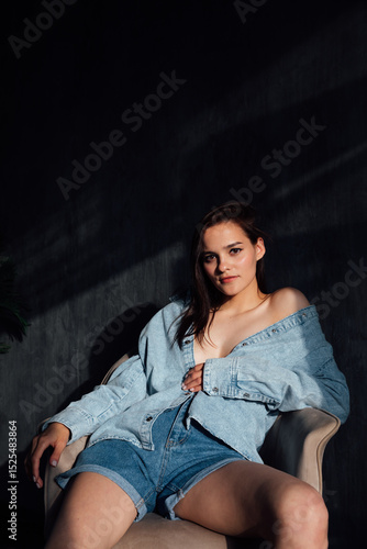 Brunette in off-the-shoulder denim on background