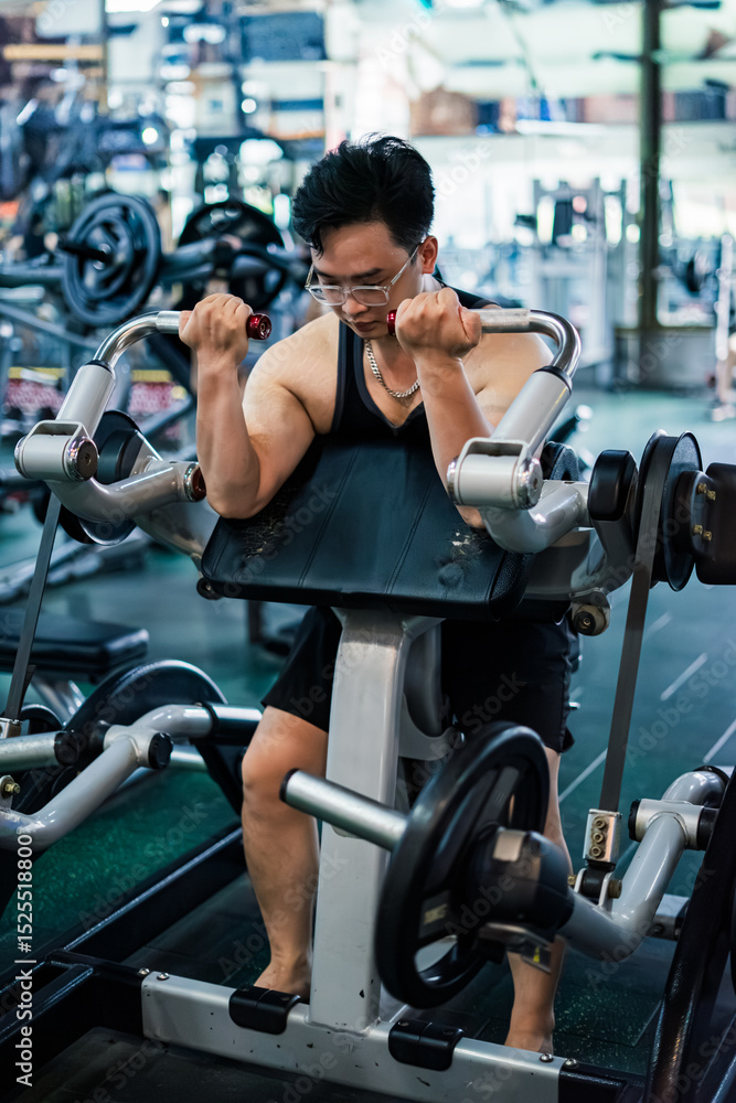 Young Asian man exercising with weights in a gym focusing on bicep curls during the evening workout session Young Asian man exercising with weights in a gym focusing on bicep curls during the evening workout session