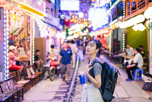 Young traveler explores vibrant street decorated with lights in an Asian city during evening hours, enjoying the lively atmosphere and local culture