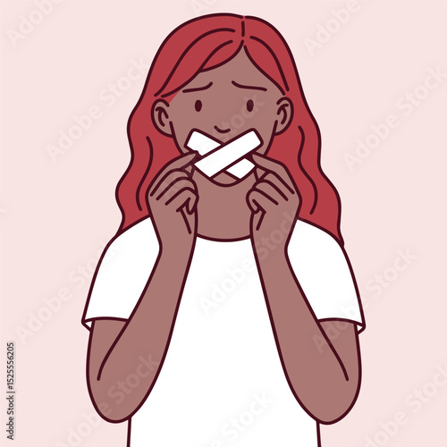 Red-haired black dark brown skinned woman starts removing tape from her mouth. Symbol of breaking silence, personal freedom, and reclaiming voice