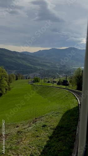 Scenic view of rolling green hills and mountains under a bright sky at midday in a tranquil landscape