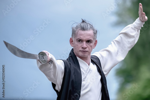Kung Fu training. The man performs daily exercises with a sword. Horizontal image.