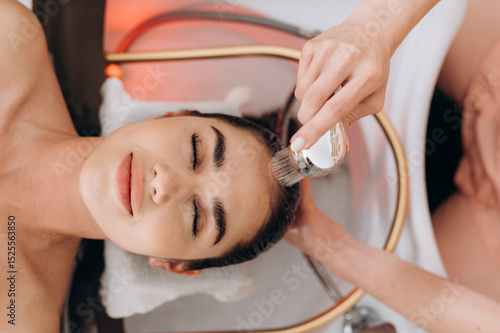Top‑view scalp spa hair wash on long dark hair in professional salon setting