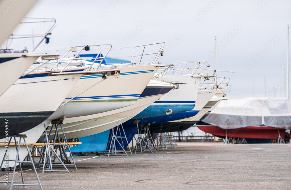 Fototapeta premium Line of moored boats on dry marina platform.