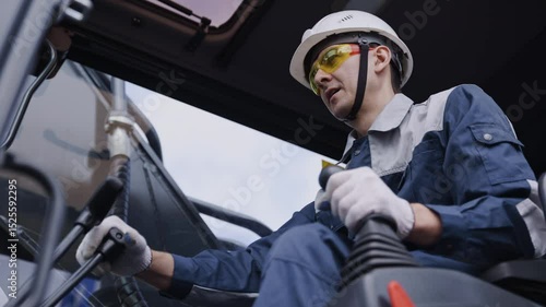 Man driver builder operate crane or excavator at construction site with sun light. Portrait Industry worker.