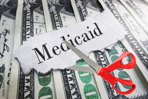 Medicaid newspaper headline on cash with scissors about to cut