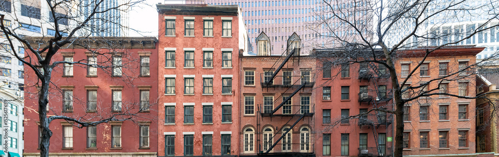 Fototapeta premium Old historic apartment buildings on Pearl Street in New York City with the modern buildings of the financial district in the background