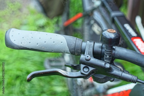 one comfortable gray new modern rubber soft stylish handle on black iron handlebar with brake lever and round bell sport mountain bike daytime outdoor