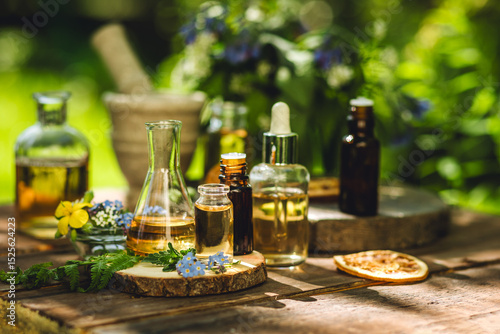 Concept of pure natural ingredients for cosmetic production. Alternative herbal medicine. Bottles of tincture or potion, organic essential oils, dry healthy herbs, floral extracts on wooden table