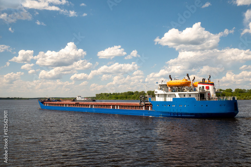 A cargo ship, a cargo ship or an oil tanker, is moving along the river. Logistics and cargo transportation by ship, Freight transportation, river navigation