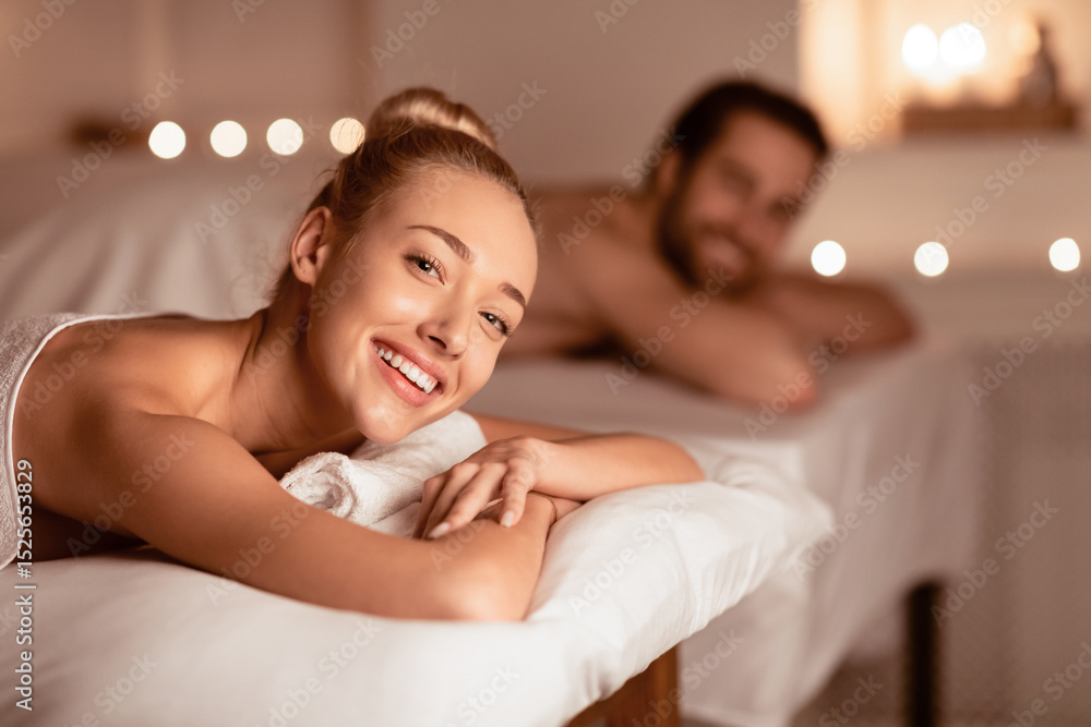 Obraz premium Happy Lady Relaxing At Spa With Husband, Smiling To Camera Enjoying Aromatherapy Lying Wrapped In White Towels, Waiting For Massage Beauty Treatment. Wellness And Relaxation Concept. Selective Focus