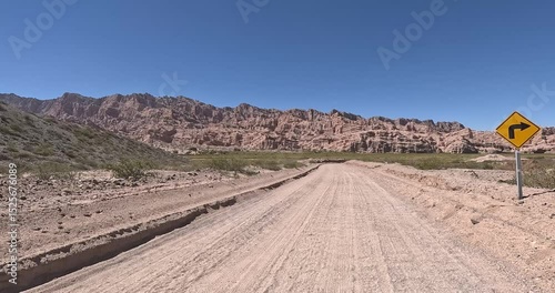 Dirt road in the desert named Quebrada de las Flechas with mountains of sedimentary rocks in Salta Province, Argentina