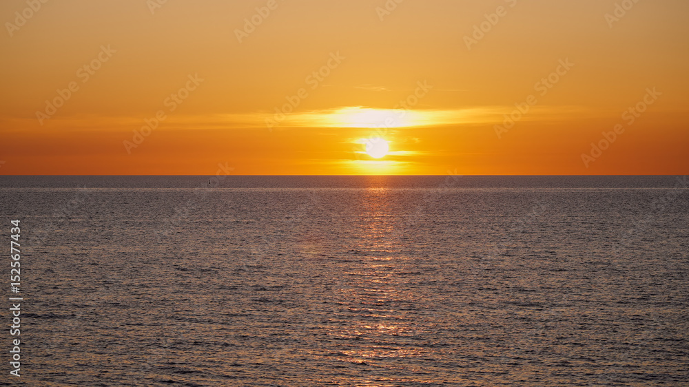 Obraz premium Breathtaking sunset over a calm ocean, creating a magical atmosphere with warm colors during twilight
