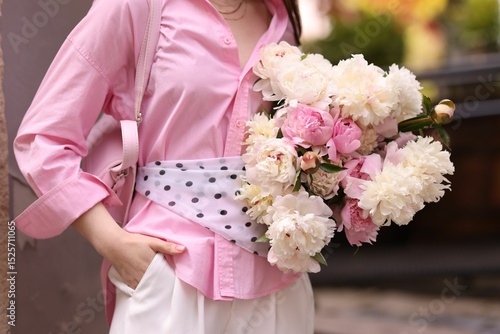 Quadro su tela Stylish woman with beautiful peonies on city street, closeup