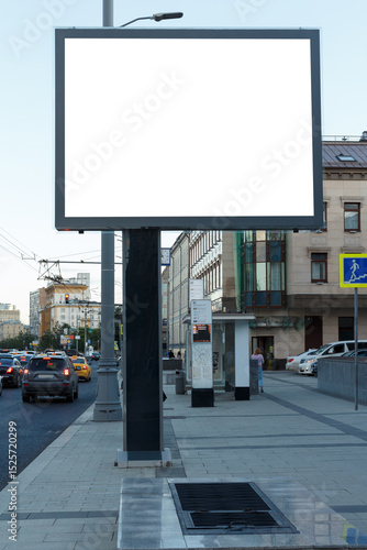 Empty billboard in the evening city on the sidewalk by the road. Mock-up.