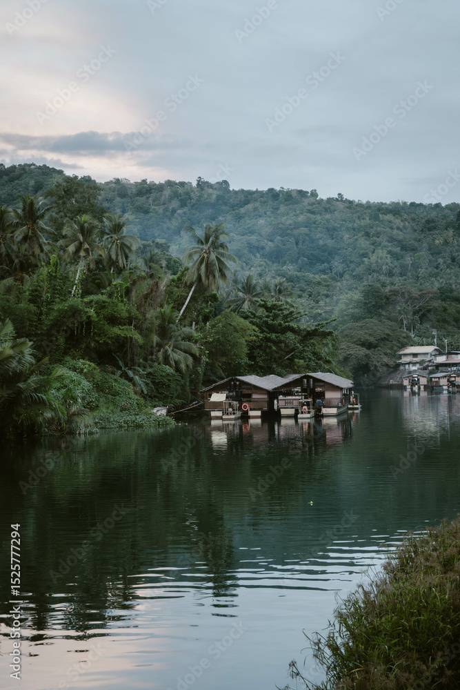 Fototapeta premium Wooden boats floating on the water of the Loboc River surrounded by lush greenery and palm trees outdoor during sunset on Bohol island in the Philippines in Asia.
