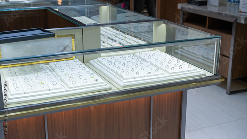 Photography Close-up of luxury rings displayed in a glass jewelry case inside a modern jewelry store, showcasing various diamond and gemstone designs in an elegant presentation