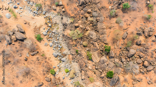 An aerial shot reveals a dried-up riverbed amongst scattered rocks sparse vegetation a sun-baked, arid landscape.