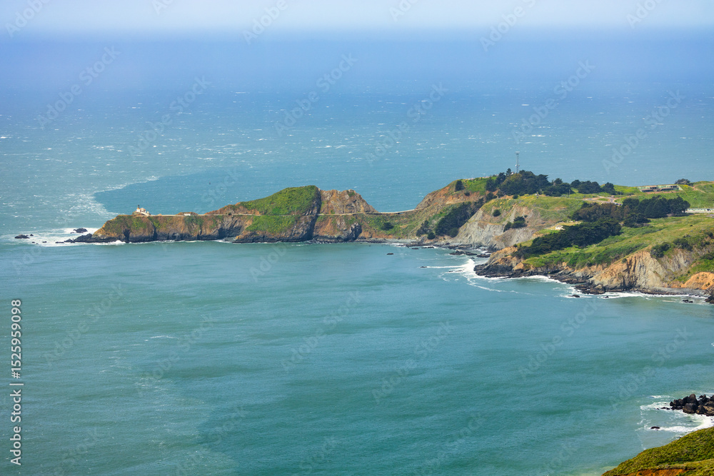 Fototapeta premium Scenic panoramic view of Marin Headlands with winding road, lush green hills, and Pacific Ocean coastline on a clear spring day, California nature landscape