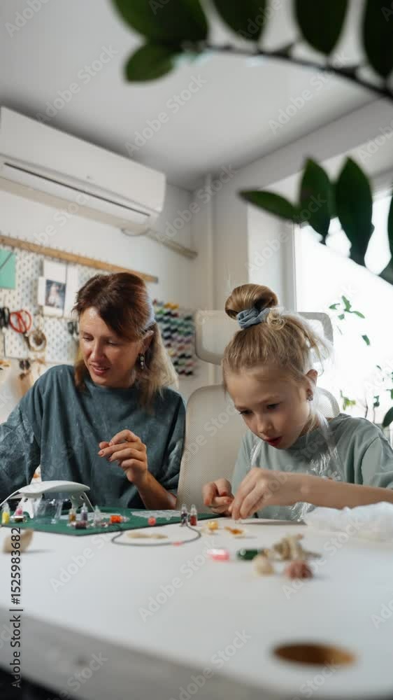 Focused little girl and her mom adding colorful sparkles into jewelry molds during homemade resin project. Hobby time and crafting together concept. Focused little girl and her mom adding colorful sparkles into jewelry molds during homemade resin project. Hobby time and crafting together concept.