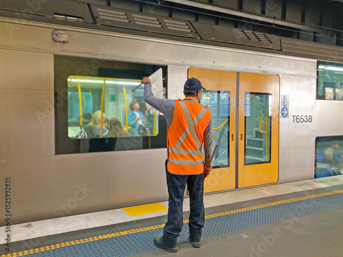 A rail worker waving a white flag signals to the train driver that it is safe to proceed