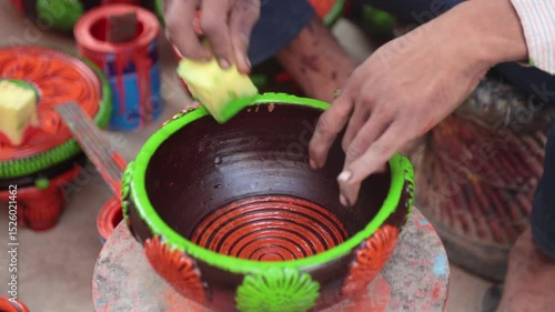 A skilled labourer or laborer paints a clay pot using vibrant colors and a sponge, showcasing traditional craftsmanship and artistic technique in a hands-on pottery decoration process. 4k Video 50 fps
