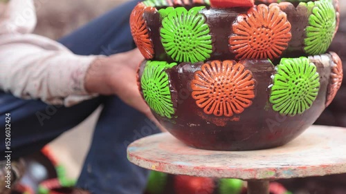 A skilled labourer or laborer paints a clay pot using vibrant colors and a sponge, showcasing traditional craftsmanship and artistic technique in a hands-on pottery decoration process. 4k Video 50 fps