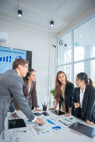 Group of confident professional business people pointing at graphs and charts to analyze marketing data to plan new sales strategies to increase productivity in modern office.