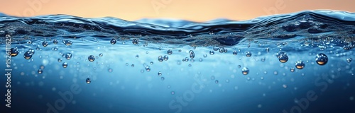 Close-up view of clear blue water surface with air bubbles rising and gentle waves under soft orange sky