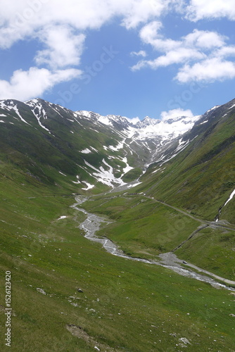 magnificent mountain landscape with snow-capped peaks, white clouds and blue sky in sunny day in summer, Switzerland