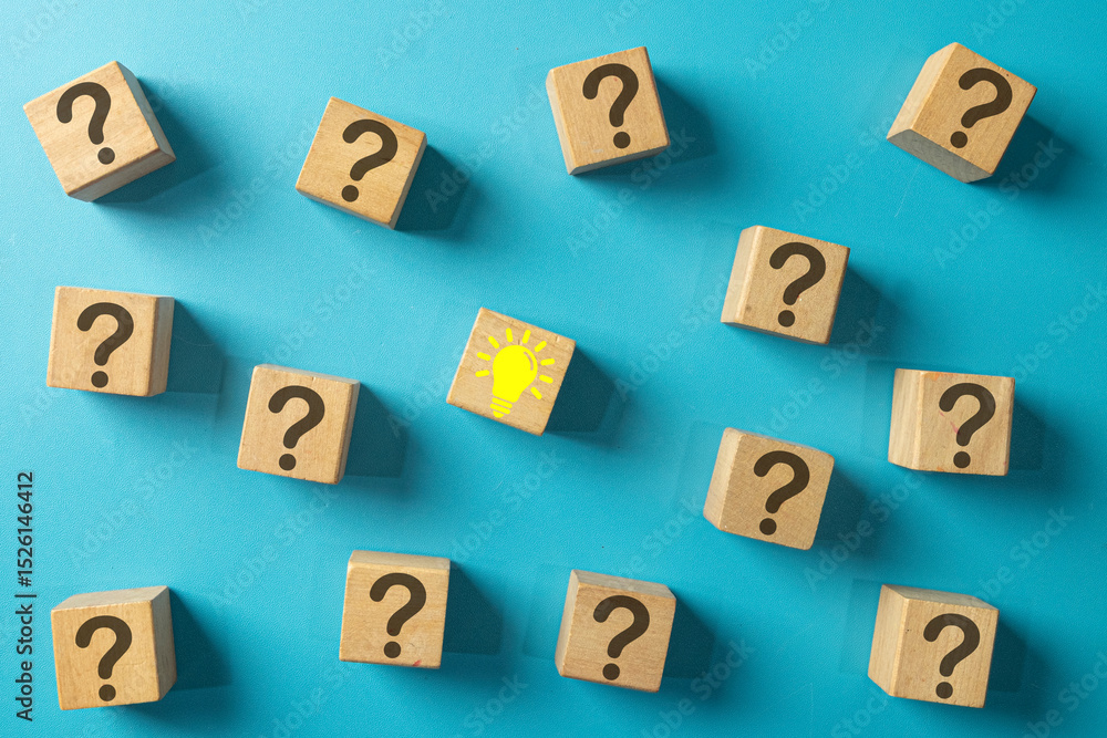 Obraz premium A single wooden block with a yellow lightbulb idea icon surrounded by blocks with question marks. Concept for finding a solution, problem-solving, answering questions, and creative thinking.